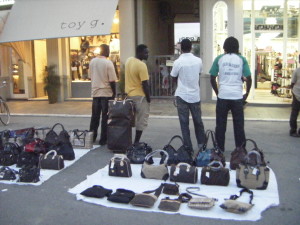 Alcuni venditori ambulanti con la loro "merce" davanti ai negozi